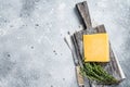 Hard cheese with knive on wooden cutting board. Parmesan. Gray background. Top view. Copy space