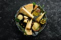 Hard cheese with olives and cheese knife on black stone background. Parmesan. Top view. Royalty Free Stock Photo