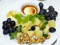 Hard cheese on a plate served with grapes, walnuts and honey Royalty Free Stock Photo