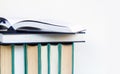 Hard cover books stacked on white surface with copy space and one book open on them Royalty Free Stock Photo