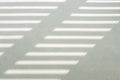 Hard, diagonal floor shadows on gray tiles from window shutters or blinds. Attractive abstract half frame composition