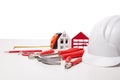 Hard hat, construction tools and model of house on white background. Concept of construction