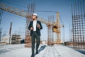 In hard hat, holding plan in hands. Businessman in formal clothes is on the construction site at daytime Royalty Free Stock Photo