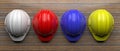 Hard hats various colors on wood, top view. 3d illustration