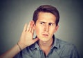 Hard of hearing man placing hand on ear listening to gossip Royalty Free Stock Photo