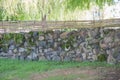 Long solid rural design fence made from aged stones and made decorative of bamboo