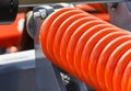 Hard orange spring made of steel. Part and detail of industrial or agricultural machine Royalty Free Stock Photo