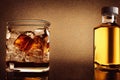 Glass with ice cubes on the rocks and gold bottle liquor. Hard strong alcoholic drinks and distillates. Generative AI Royalty Free Stock Photo