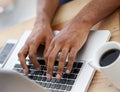 Hard at work. Cropped view of a businessmans hands as he types on his laptop.