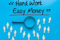 Hard Work - Easy Money Sign on white paper. Man Hand Holding Paper with text. Isolated on Workers concept, Magnifying glass. Blue Royalty Free Stock Photo
