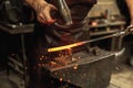 Close-up working powerful hands of male blacksmith forge an iron product in a blacksmith. Hammer, red hot metal and Royalty Free Stock Photo