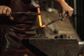 Close-up working powerful hands of male blacksmith forge an iron product in a blacksmith. Hammer, red hot metal and