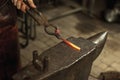 Close-up working powerful hands of male blacksmith forge an iron product in a blacksmith. Hammer, red hot metal and