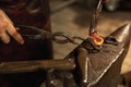 Close-up working powerful hands of male blacksmith forge an iron product in a blacksmith. Hammer, red hot metal and