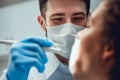 Hard work. Selective focus of male hands carried dental tools while serious male dentist putting on mask. Close up view Royalty Free Stock Photo