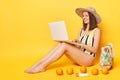 Hard working attractive woman wearing one piece swimming suit posing isolated over yellow background working on resort sitting Royalty Free Stock Photo