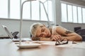 After hard working day. Young and tired tattooed business woman with short haircut sleeping at her workplace on desk Royalty Free Stock Photo