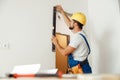 Hard working handyman, builder in uniform measuring the wall using bubble level