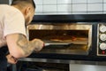 Hard-working man cooking delicious pizza in the oven Royalty Free Stock Photo