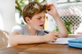 Hard-working sad school kid boy making homework during quarantine time from corona pandemic disease. Upset tired child Royalty Free Stock Photo