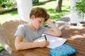 Hard-working sad school kid boy making homework during quarantine time from corona pandemic disease. Upset tired child Royalty Free Stock Photo