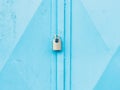 Hardened padlock hang in eye bolt on blue industrial metal door Royalty Free Stock Photo