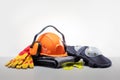 Hardhat, knee pads, earmuffs, gloves, goggles on grey color surface