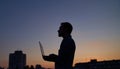 Freelancer developer in silhouette using laptop outdoor at sunset, working hard Royalty Free Stock Photo