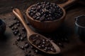 On a hardwood background, there are scoops of dark roasted coffee beans