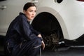 Hardworking female mechanic changing car wheel in auto repair workshop. Oxus