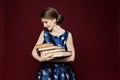 Hardworking female student in blue dress keeping books in hands and looking at the camera. Beautiful girl with blue eyes