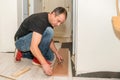 Hardworking man with a physical handicap in his hand that has several amputated fingers working on laying the floor of his house.