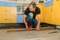 Hardworking man with a physical handicap in his hand that has several amputated fingers working on laying the floor of his house.