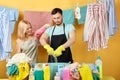 Hardworking man squeezes out wetclothes, while his wife controlling his work