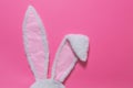 Hare ears made of white fur on pink pastel background. The concept of Easter