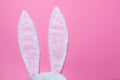 Hare ears made of white fur on pink pastel background. The concept of Easter