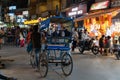 Rickshaw driver walks his vehicle through the crowded night market