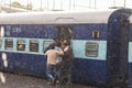 Haridwar, India - March 11, 2017: Crowd boarding train in Haridwar railway station under heavy monsoon rain. Young boys fighting t