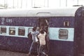 Haridwar, India - March 11, 2017: Crowd boarding train in Haridwar railway station under heavy monsoon rain. Young boys fighting t