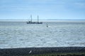 Harlingen,the Netherlands,July 23,2020:Wadden sea with windsurfer and old traditional sailing ship, black stone dike