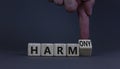 From harm to harmony. Businessman turns the wooden cube and changes word harm to harmony. Beautiful grey table, grey background.