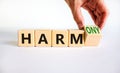 From harm to harmony. Businessman turns the wooden cube and changes word harm to harmony. Beautiful white table, white background