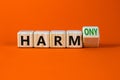 From harm to harmony. Turned a wooden cube and changed word harm to harmony. Beautiful orange table, orange background. Business