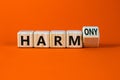 From harm to harmony. Turned a wooden cube and changed word harm to harmony. Beautiful orange table, orange background. Business