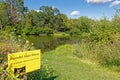 yellow Harmful algal bloom danger sign at small pond in Summer