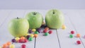 Apples and candies on a white wooden table. Harmful and healthy food on a white background.