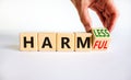 From harmful to harmless. Businessman turns the wooden cube and changes word harmful to harmless. Beautiful white table, white