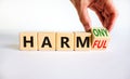 From harmful to harmony. Businessman turns the wooden cube and changes word harmful to harmony. Beautiful white table, white