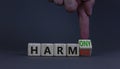 From harmful to harmony. Businessman turns the wooden cube and changes word harmful to harmony. Beautiful grey table, grey