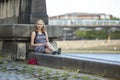 ÃÂ¡harming girl sitting on a stone promenade.